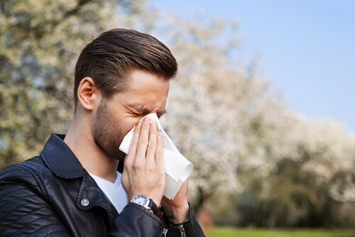 Man sneezing into tisuse